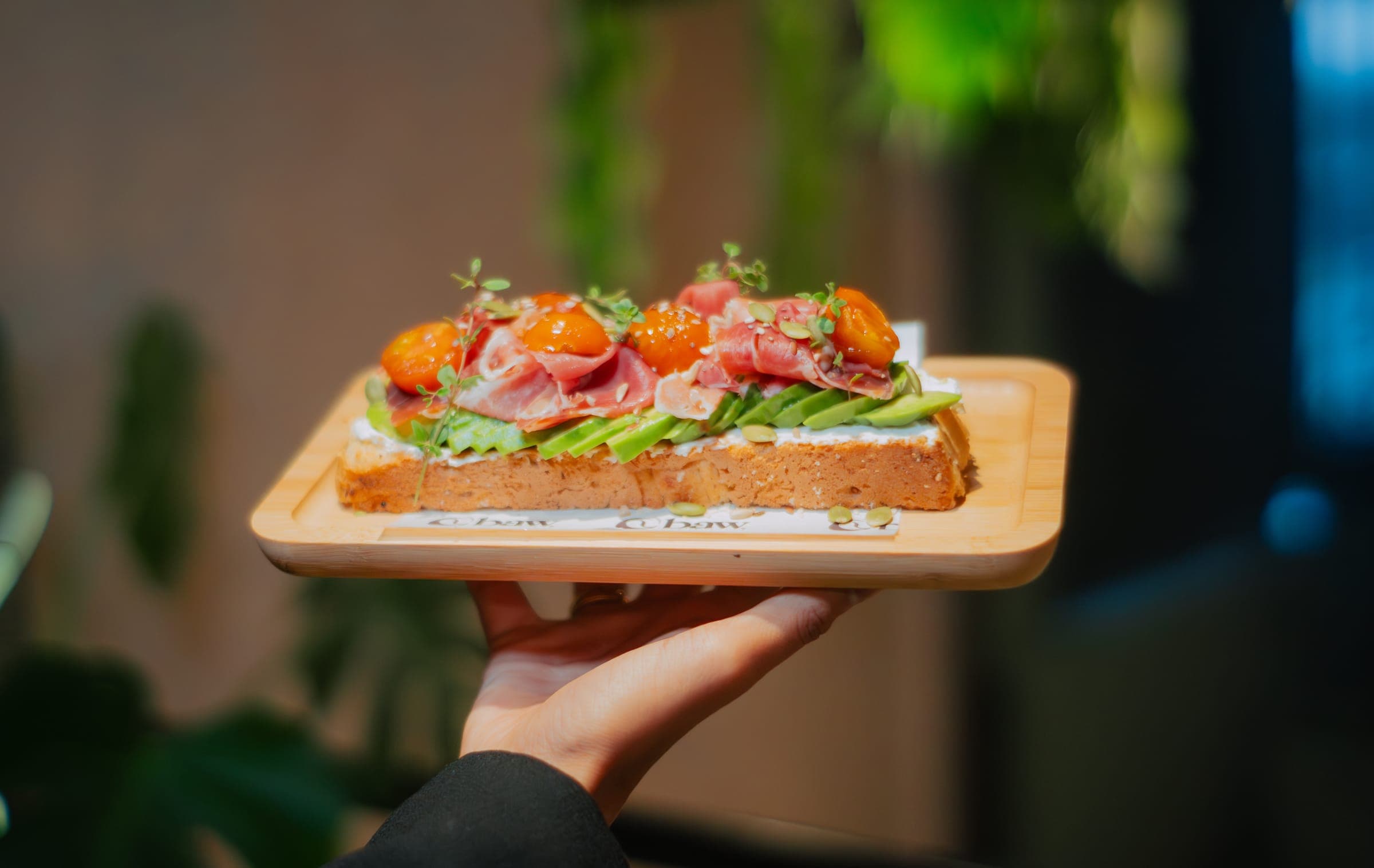 Tostada de palta y jamón servida sobre una tabla de madera de BAW Coffee
