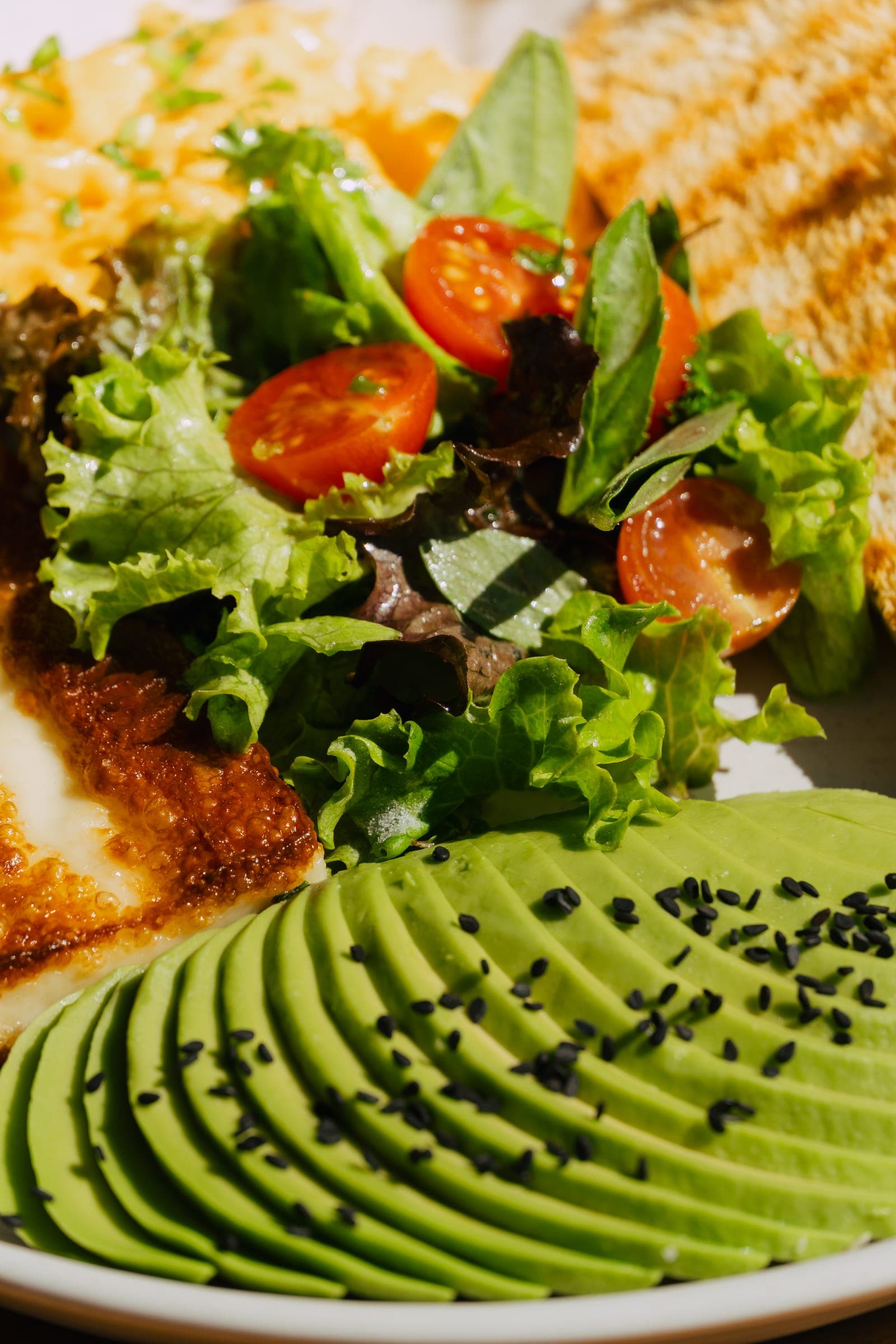 Detalle de palta, tomates y hojas verdes en un plato de BAW Coffee