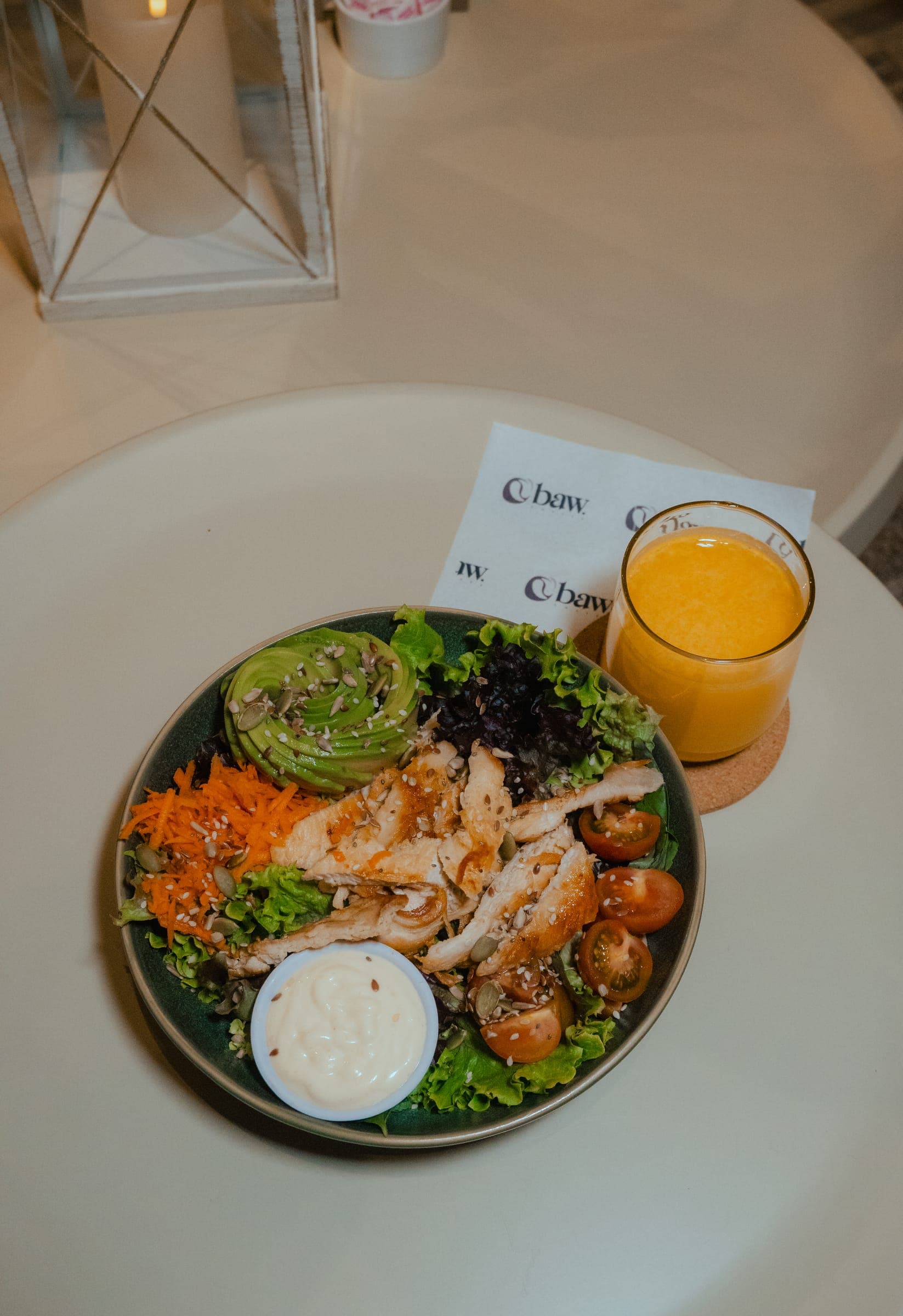 Ensalada y vaso de jugo sobre una mesa de BAW Coffee