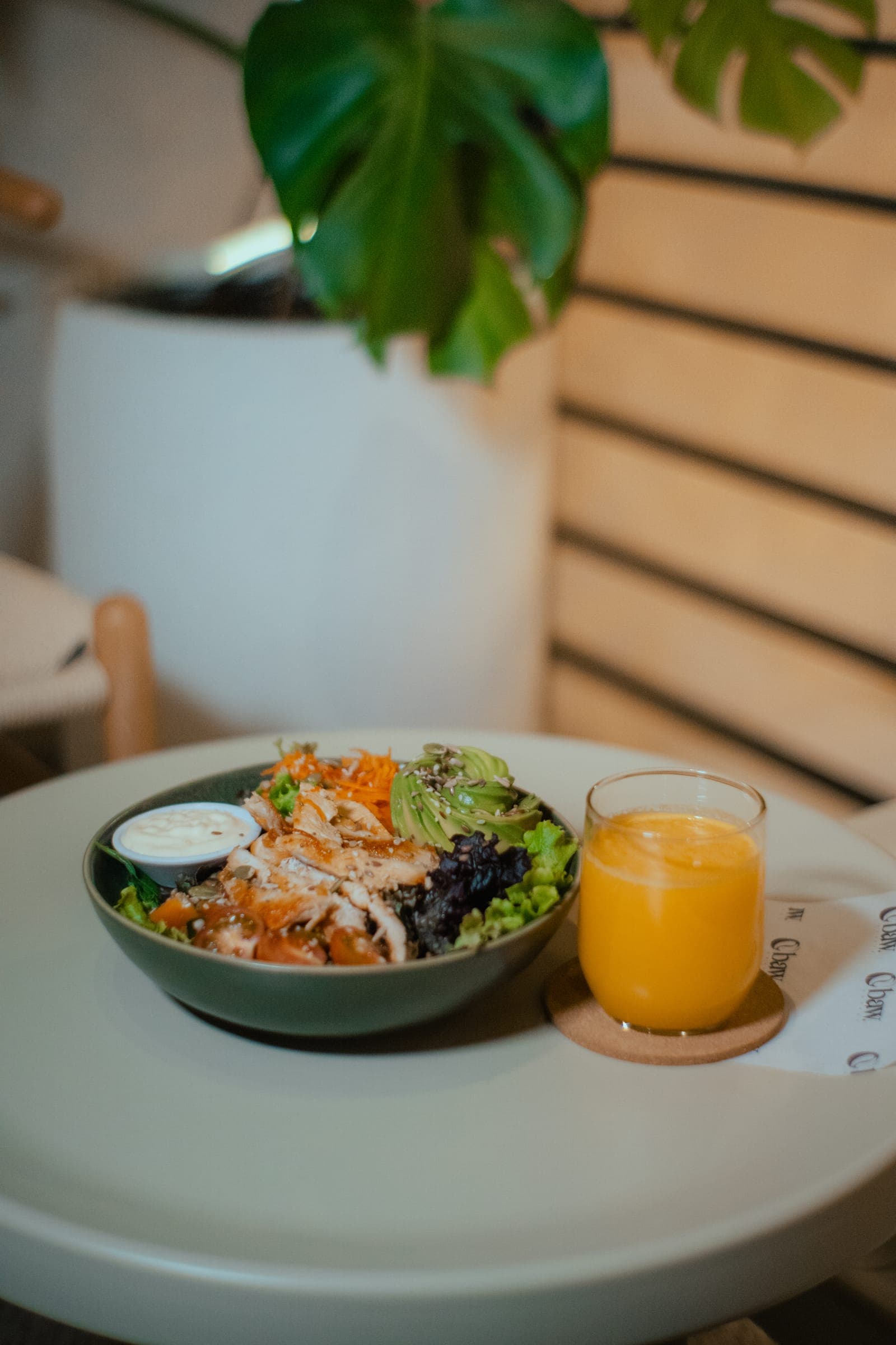 Mesa con ensalada y jugo junto a una planta en BAW Coffee